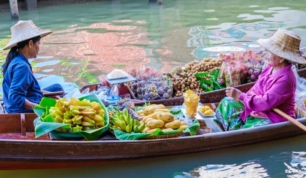 A single boat with two vendors at the Damnoen Saduak floating market in Thailand, showcasing a variety of goods for sale